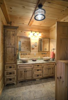 a bathroom with two sinks and wooden cabinets in the corner, along with a light fixture