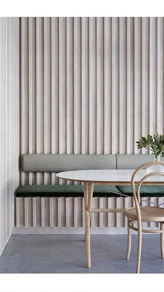 a white table and two green chairs in front of a wall with vertical slats