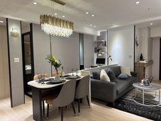 a modern living room and dining area with grey couches, white table and chairs