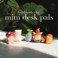 the small toy animals are lined up in front of some green plants and text that reads handmade clay mini desk pals