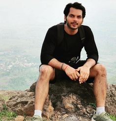 a man sitting on top of a rock with his legs crossed