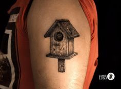 a birdhouse tattoo on the right arm