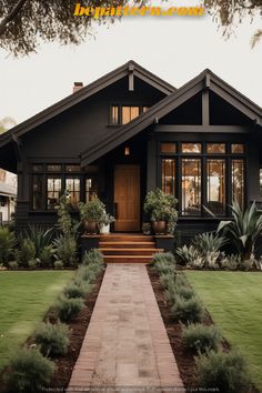 a house that is in the middle of some grass and plants on the front lawn