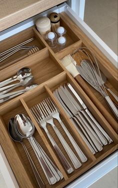 an open drawer filled with silverware and utensils on top of a counter