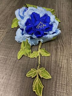 a blue flower with green leaves on a wooden surface