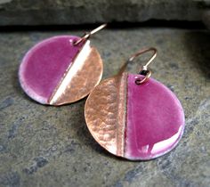 two tone pink and gold disc earrings on top of a granite slab with a rock in the background