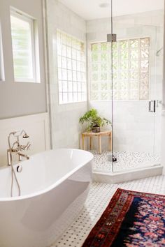 a white bath tub sitting next to a walk in shower and a rug on the floor