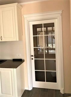 an empty kitchen with white cabinets and black counter tops on either side of the door