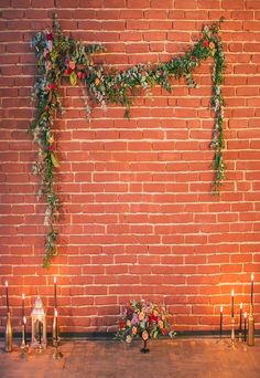 a brick wall decorated with greenery and candles