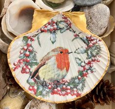 a paper plate with a bird on it surrounded by seashells and pine cones