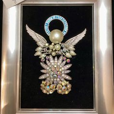 a framed photo with an angel brooch in it