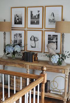 there are pictures on the wall and vases with flowers in them next to a wooden table