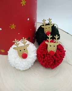 three pom - poms with reindeer faces on them are sitting next to a red and white box