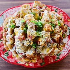 a red plate topped with potato salad on top of a wooden table next to a fork