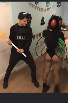 two people dressed up in costumes and one is holding a bat