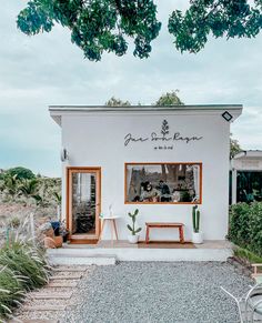 a white building with plants and chairs outside