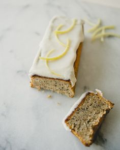 two slices of cake with white frosting and lemon zest on the top one slice is cut in half