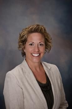 a woman wearing a white blazer and black shirt smiling at the camera with her hands in her pockets