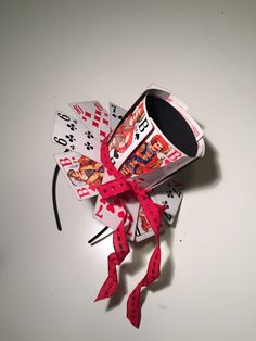 a coffee cup and playing cards tied to a string on a white table with a red bow