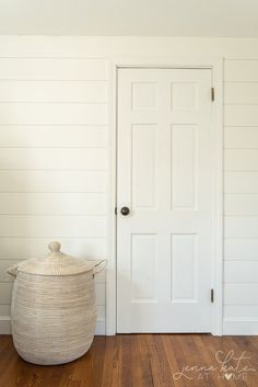 a white door with a basket in front of it on the floor next to a wooden floor