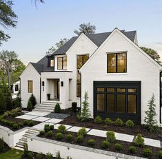 a white house with black windows and landscaping