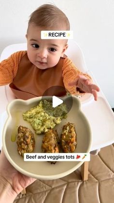 a baby sitting in a highchair holding a plate with meat and veggies