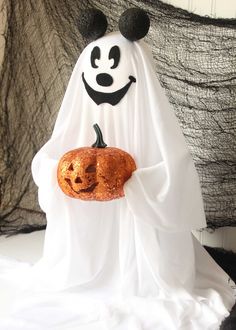 a white ghost holding a pumpkin in it's hands