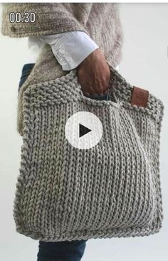 a person holding a knitted bag with a video playing on the screen below it