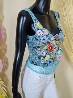 a mannequin wearing a blue crochet top with flowers on it's chest