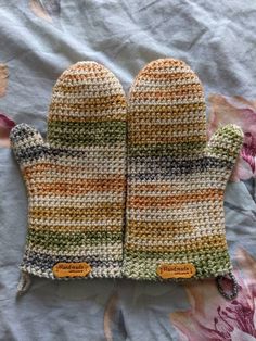 two knit mittens sitting on top of a bed