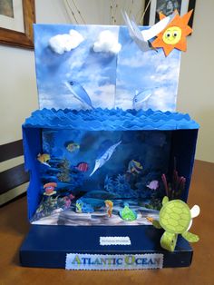 an aquarium made out of cardboard with paper fish and sea creatures on it, sitting on a table