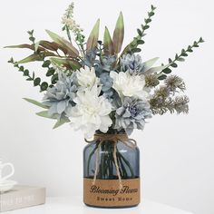 a vase filled with blue and white flowers on top of a table next to a book