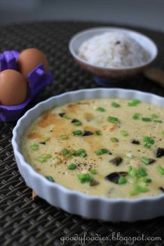 a bowl filled with soup next to an egg and some other food on a table