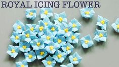 small blue flowers with yellow centers sitting on top of a gray surface next to the words royal icing flower