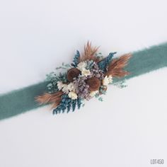 an arrangement of dried flowers on a green ribbon