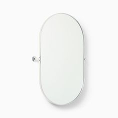 an oval mirror on the wall with a metal hook in it's center and one section missing