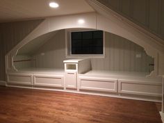 an empty room with built - in shelves and drawers on the wall, under a slanted ceiling