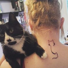 a black and white cat on the back of a woman's neck with a tattoo