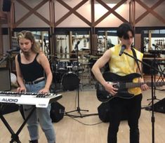 two young people are playing instruments in a recording studio while another person stands behind them