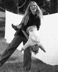 a woman is holding a dog in the air while another person holds her upside down