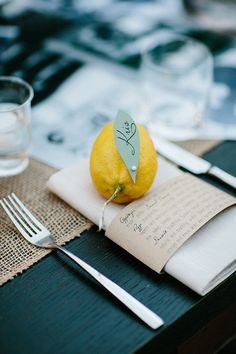 an orange sitting on top of a napkin next to a fork and knife