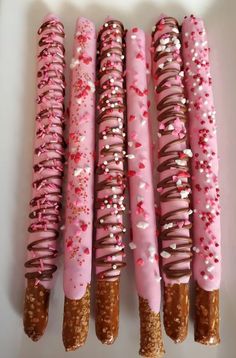 five donuts with pink icing and sprinkles are lined up in a row