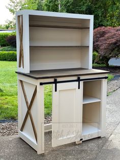 an old dresser is painted white and has black trim on the top, with a wooden cross at the bottom