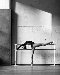 a woman is doing a handstand on a bench in front of a wall