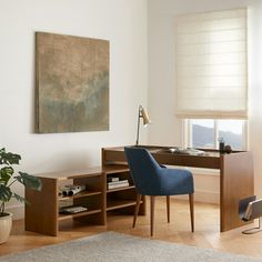 a room with a desk, chair and painting on the wall next to a potted plant