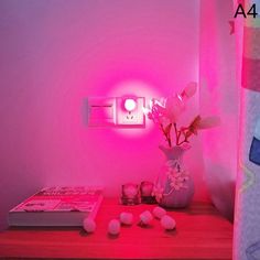 a pink light shines in the corner of a room next to a vase with flowers