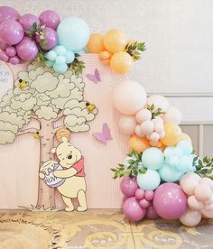 winnie the pooh balloon arch with balloons on it and some decorations in front of it