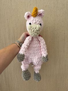 a crocheted pink stuffed animal with a yellow horn