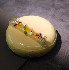 a yellow cake with flowers on it sitting on a black table next to a knife