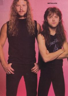 two men standing next to each other in front of a pink background with their arms crossed